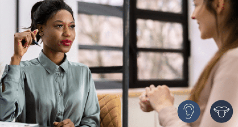 Two women engaged in an assessment dialogue, one serving as the Assessor, in a private office space. The learner has a visual impairment. so the Assessor is providing support and guidance